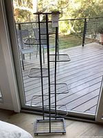 Full view of the metal gray foldable plant stand in front of sliding glass door, showing structure and capacity for plants.