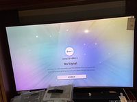 Full front view of 55" curved TV powered on showing screen and accessories