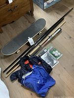 Overview of lot showing skateboard, martial arts sticks, baseball bat, jacket, shirt, swim cap and balls