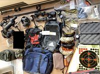 Overview of lot items laid out: scopes, bags, eyewear, watch, adhesive targets, ear protection, and accessories