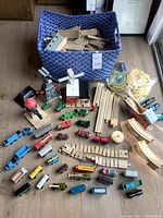 Complete view of container with wooden trains and track pieces around it.
