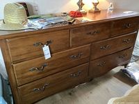 Front view of Thomasville solid wood dresser showing nine drawers with metal handles and a medium brown wood finish.