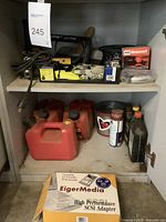 Shelf with multiple gas cans and containers, SCSI adapter box, metal chain container and spray cans.
