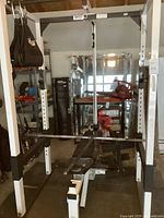 Front view of full power rack with bench inside, pulley system, and weight vest attached, in garage