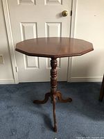 Front profile of the 12-sided dark brown pine decorative table showing the turned pedestal base and tripod carved legs.