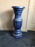 Side view showing detailed carved body and solid octagonal base of one blue pedestal stand.
