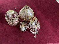 All four items together: two beaded chandeliers, a medium mother of pearl fixture, and a large mother of pearl light shade on red carpet