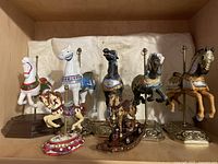 Group shot of all seven carousel horse figurines, five large and two smaller, showing details and bases.
