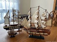 Three ship models on a table from front angle showing two large schooners and mini schooner