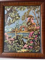Full view of the framed needlepoint artwork showing the river mill and surrounding landscape