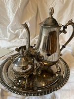 Full set of silver plated coffee pot, creamer, sugar bowl, and round serving tray on white background