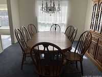 Oval table set up with eight chairs in dining room under chandelier