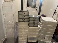 Photo showing the various plastic drawer units and clear bins arranged together near a door indoors.