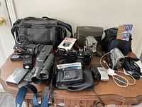 Overview of all lot contents including cameras, camcorders, cases and accessories