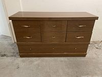 Front view of the vintage brown lacquer horizontal dresser highlighting six drawers with metal handles and detailed curves on central drawers.