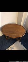 Oval light brown wooden table top with a slightly curved lip and smooth finish.