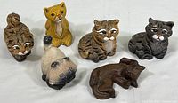 Set of six small cat figurines in various colors and poses, arranged on a white surface showing scale and condition.