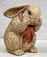 Front view of hollow cast ceramic rabbit figurine wearing pink scarf, showing detailed fur texture and facial features.