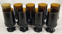 Nine amber smoke glass goblets arranged in rows, showing uniformity of eight glasses and one slightly different.