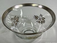 Front and inside view showing clear glass bowl with silver rim and silver and gold leaf damask pattern.