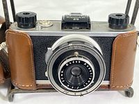 Front view of vintage Kodak 35 film camera with brown leather case attached partially on front and sides.