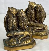 Pair of bronze-colored cast metal owl bookends showing two owls sitting closely on a branch with an octagonal base.