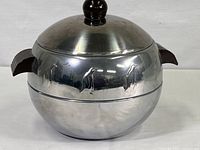 Full view of the stainless steel insulated server with embossed penguin figures and brown handles.