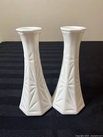 Two white milk glass bud vases with starburst geometric embossed pattern, front view showing shape and design.
