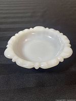 Top angled view of the white milk glass dish showing the scalloped and beaded edge design over black background.