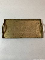 Top view of brass tray showing floral engraved pattern and handles on each side