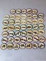 Photo showing multiple plastic tokens featuring vintage car images with numbers and colored rims, arranged in a grid.