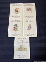 Five Beatrix Potter hard cover books laid out facing front covers, showing title and illustration of animal characters.