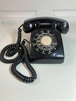 Front angle showing rotary dial, handset, and coiled cord.