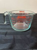 Clear glass Pyrex measuring cup showing red measurement markings and handle.