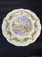 White collector plate with scalloped edges, holly and berry border, detailed illustration of mice dining at a candlelit supper in a hall, signature Jill Barklem