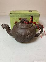 Brown ceramic dragon teapot with box in background