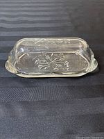Butter dish top view, shows floral embossed pattern and scalloped edges on the lid