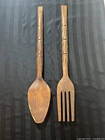 Top view of the wooden spoon and fork showing the carved handle designs and utensil heads.