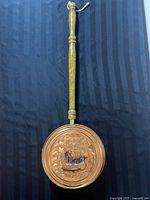 Front side of copper and brass bed warmer showing embossed design of horse with foliage
