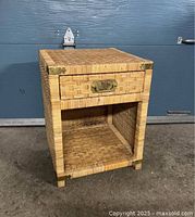 Front view of vintage rattan wicker nightstand showing drawer with brass handle and open shelf below.