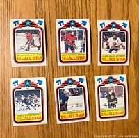 Six front-facing 1978-79 O-Pee-Chee All Star hockey cards arranged on wooden surface showing players Guy Lafleur, Larry Robinson, Clark Gillies, Darryl Sittler, Don Edwards, and Terry O'Reilly.