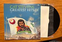Front cover of Cat Stevens "Greatest Hits" vinyl album with record partially visible.