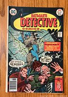 Front cover of Detective Comics #465 showing Batman with two men holding guns in a dramatic scene.