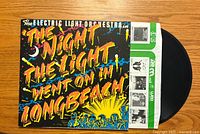 Front cover of the Electric Light Orchestra vinyl record 'The Night the Light Went On in Long Beach', showing colorful title text and crowd scene under a night sky.