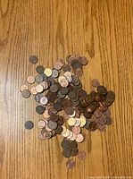 Top view of a scattered pile of US pennies on a wood surface showing mixed circulation conditions and various years.