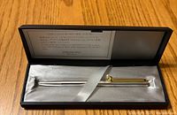 Mikimoto ballpoint pen secured inside a satin-lined black case with an informational card inside the lid.