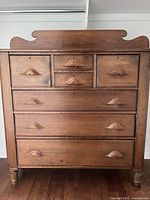 Front view of dresser showing all seven drawers and removable wooden backboard accent behind