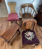 Photo shows an antique wooden folding table, embroidered chair with red cushion, wooden captain's chair with spindled back, and carved chair with floral needlepoint upholstery.