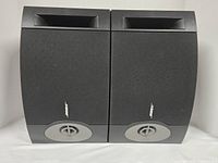 Front view of the pair of Bose 201 V speakers showing fabric covers, front-facing ports, and curved front design with control knob below the logo.