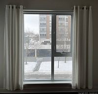 Cream-colored drapes hung on window with silver curtain rod.